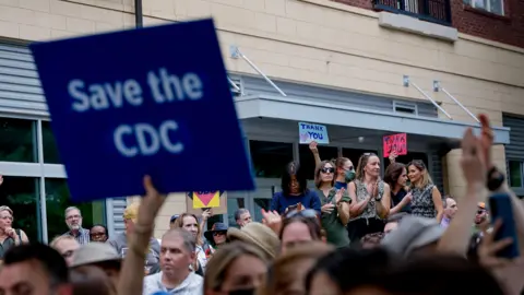 EPA Current and former CDC workers clapping and holding signs in support of recently resigned leaders
