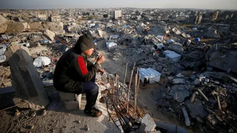 Reuters a boy sees destroyed buildings at North Gaza (26 February 2025)