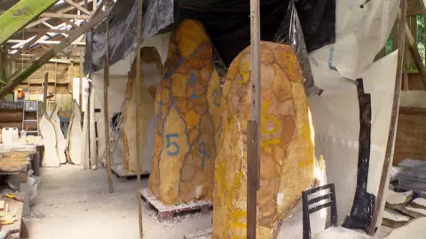 Three tall structures in a shed which will become bronze-covered modern monoliths