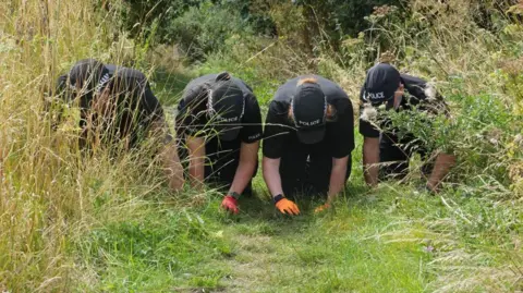 John Fairhall/BBC Investigators in Brantham conducting fingertip searches in an area