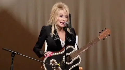 Dolly Parton with a black guitar