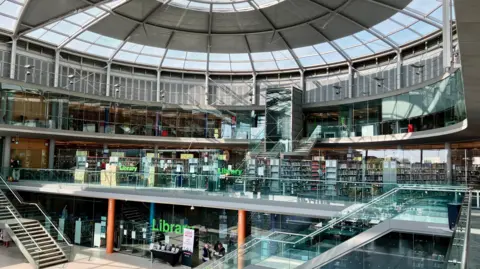 David Freezer/BBC A view of the outside of the library in Norwich. It has a glass window and a sign on it telling people the library is closed. Books and staircases can be seen inside and there is a table outside with a range of leaflets on it. The Forum buiding has a domed glass and steel roof.