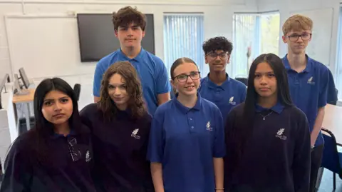 Elizabeth, Liv, Joel, Issy, Jai, Ella, and Joshua - friends in Year 10 at King's Oak Academy in Bristol - pose in their blue school polo shirts and jumpers. 