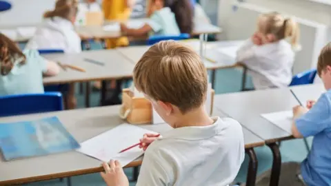 Getty Images A school pupil faces away while sat at a desk writing