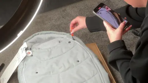 Emily filming herself unboxing a new item for a pushchair