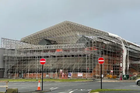 A white sheet laid over scaffolding around the Sands Centre is tattered in the wind.