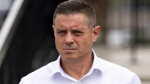 John Alford in a white shirt. He has short greying hair