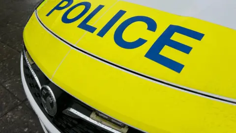 The photo shows the fluorescent yellow bonnet of a car with the word "police" in blue capital letters.