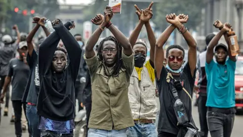 AFP Protesters with arms aloft shout slogans at riot police during a protest to oppose a proposed Finance Bill 2024, in Nairobi, Kenya, 18 June 2024