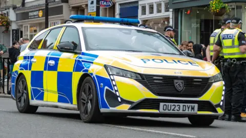 TVP Thames Valley Police car with officers standing to the right hand side of the car.