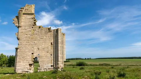 Lizzie Maher/Getty The ruins of an abbey in a field underneath a bright blue sky.