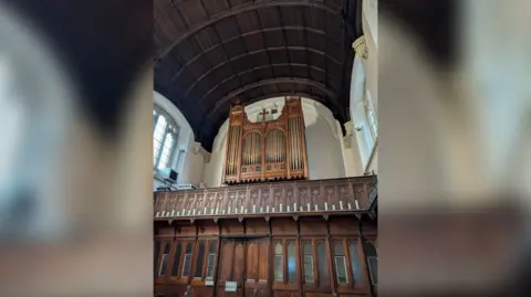 The organ pipes are installed at the back of the chapel, high in the air, above a wooden mezzanine, where the organist would play 