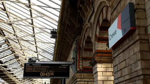 Reuters A view of Crewe Station. There's a sign saying Crewe on the wall and a information board for a train to London Euston.
