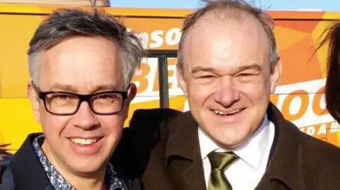 Candidate David Campanale with Sir Ed Davey standing in front of a Lib Dem bus