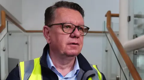 John Petticrew, a bespectacled man in a fleece and hi vis jacket