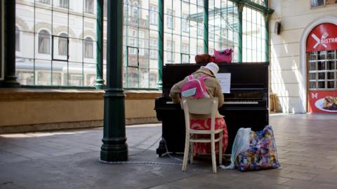 Woman plays piano in a train station
