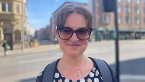 Federica smiles at the camera. She has short brown hair, she wears sunglasses and a polka dot top