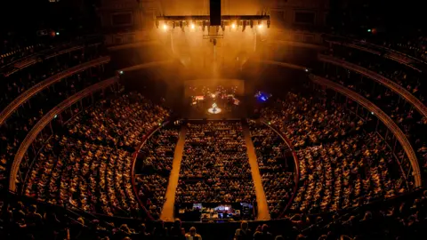 John Bird A view of a packed Royal Albert Hall during one of Jack Savoretti's solo concerts. He is on the stage with a guitar and band members behind him.