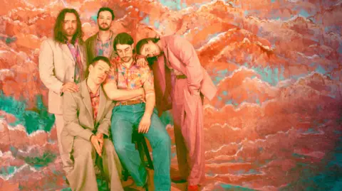 Press image of Cousin Kula - five men in loose-fitting suits in a colourful backround