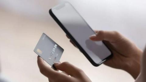 Person holding mobile phone and debit card