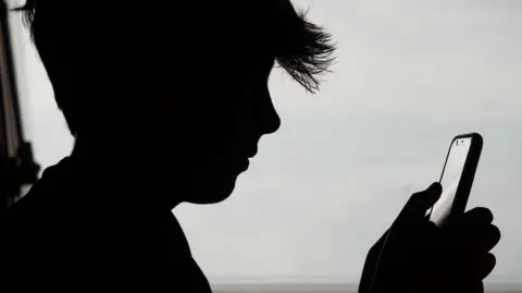Getty Images A silhouette of a boy holding a phone 