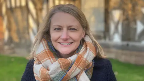 Photograph of Catherine Dewar from Historic England. She is pictured in front of Baguley Hall in Wythenshawe.
