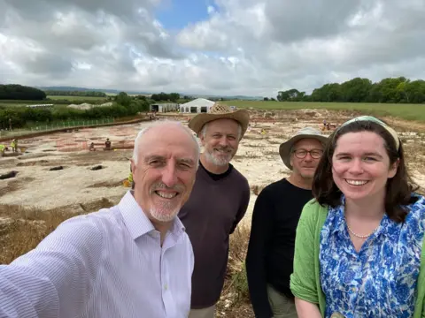 Four people in a field during an archaeological dig at Bournemouth University in Dorset