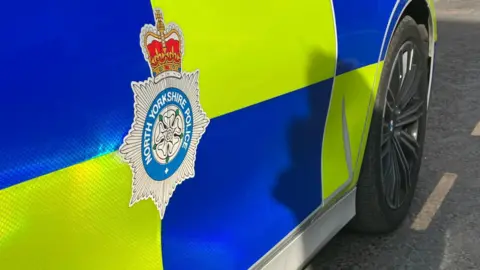 BBC Police car with fluorescent blue and yellow markings and a North Yorkshire Police emblem