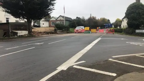 A road junction where the road ahead has been blocked by barriers and road signs.