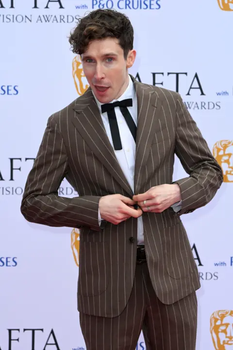 Getty Images Larry Dean in a striped brown suit