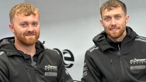 Two young men wearing black jackets branded with Crowe Racing smiling