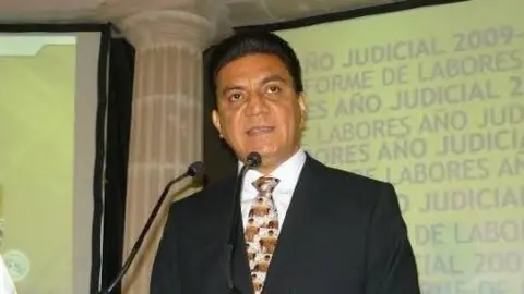 Twitter Judge Edmundo Román Pinzón, wearing a black suit and a tie, speaking at an undated event