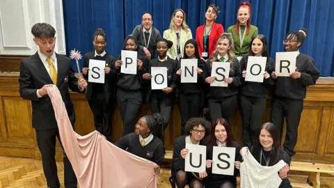 Pupils holding a "sponsor us" sign.