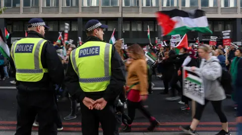 Reuters Two officers stand to the side as pro-Palestinian demonstrators walk past