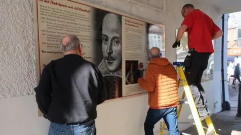 Ormskirk Community Partnership Men erect boards celebrating Ormskirk's history on the ginnel walls.