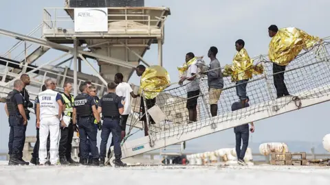 Migrants disembark from the French rescue ship Minck following their rescue at sea