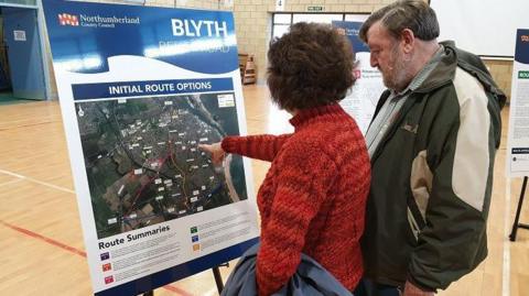 Man and woman looking at a placard of the proposed route option for a Blyth relief road