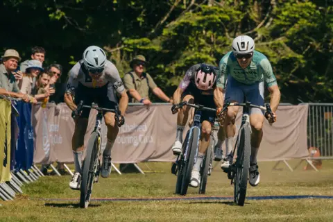 Red On Sports/Angus MacKinnon Cycle racers sprint across the grass