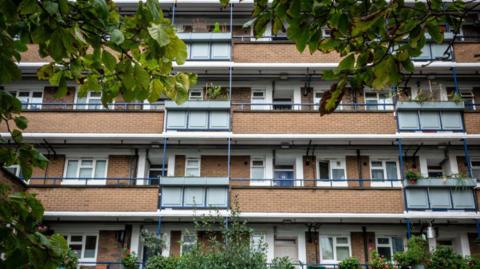 Brick flats in London and some green bushes and trees framing the view