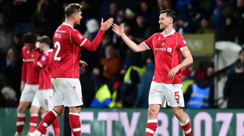 Wrexham's Dominic Hyam celebrates with team-mate Callum Doyle at the final whistle during the Emirates FA Cup Fourth Round match between Wrexham and Ipswich Town