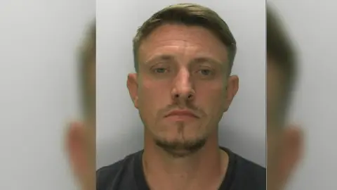 Gloucestershire Police Mugshot of Ben Townsend. He is wearing a black t-shirt and has stumble on his face.