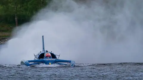 Getty Images Spray rises from the back of Bluebird - a craft looking like a cross between a boat and a plane - as it runs on Coniston Water.