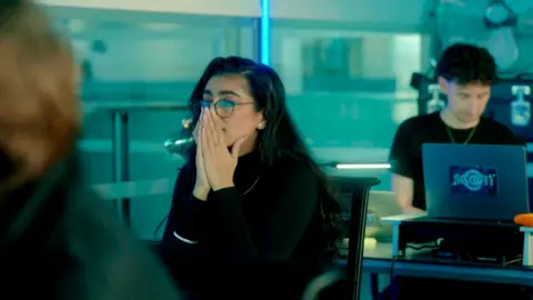 Woman in an office holds her hands in front of her mouth