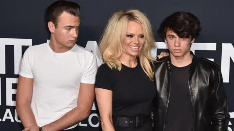 A atriz Getty Images Pamela Anderson (C) e os filhos Brandon Lee (L) e Dyland Lee (R) freqüentam Saint Laurent em Hollywood Palladium em 10 de fevereiro de 2016 em Los Angeles, Califórnia