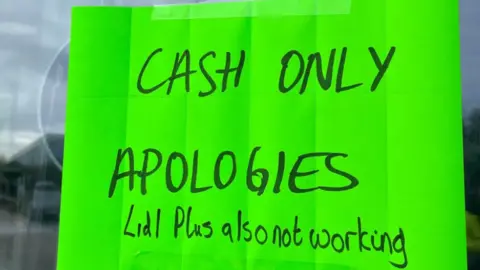 A bright green sign in a window saying "Cash only. Apologies"
