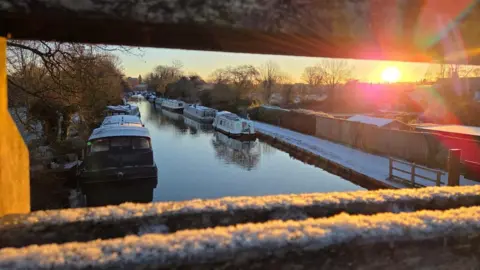 Raik Henke Narrow boats on the water seen from a bridge with snow covered roofs and paths
