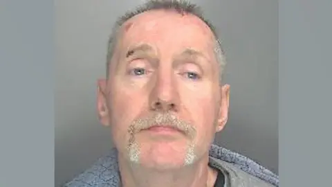 Jason O'Dell is looking at the camera in a police custody shot. He has short, greying hair and a moustache and partial beard.