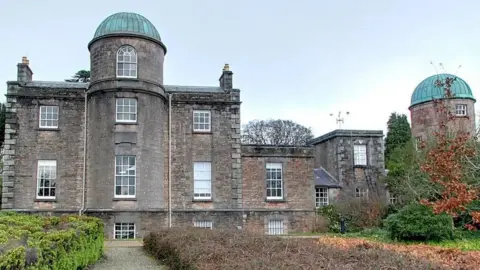 Armagh Observatory and Planetarium An exterior shot of a grey observatory building with blue copper domed roofs. The picture was taken during the day.