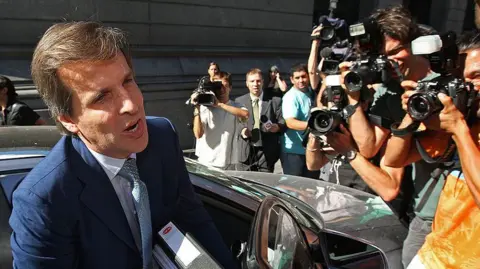AFP via Getty Images Martin Redrado emerged from a car and is swarmed by photographers and television crews in 2010, during his stand-off with the government of Cristina Kirchner