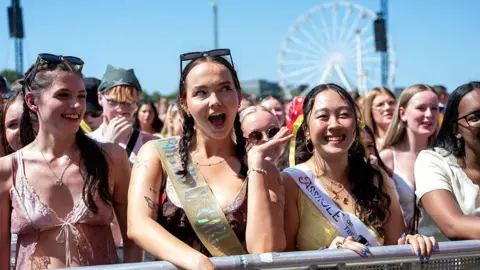 Fans in the front row at a music festival smile in the sunshine